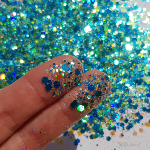 Blauwe glittermix in verschillende kleuren, maten en vormen glitter met detail op vingers