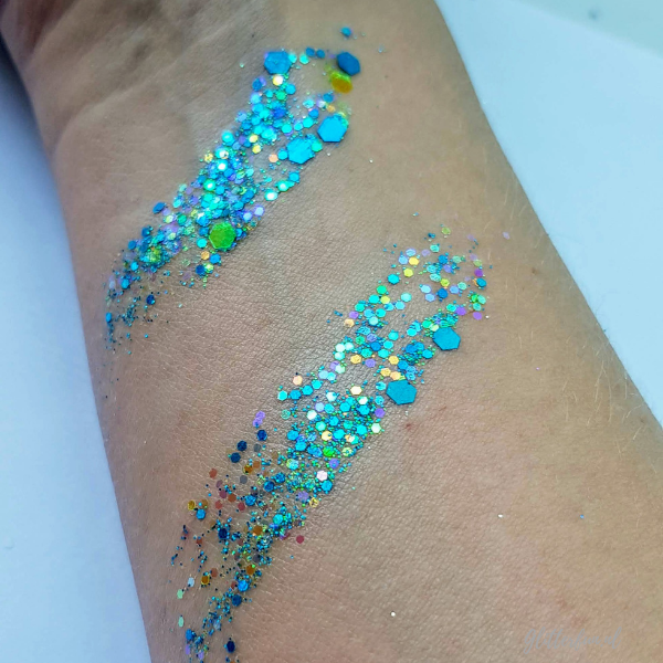 BLauwe glittermix in verschillende kleuren, maten en vormen glitter op een arm met glitterbalsem